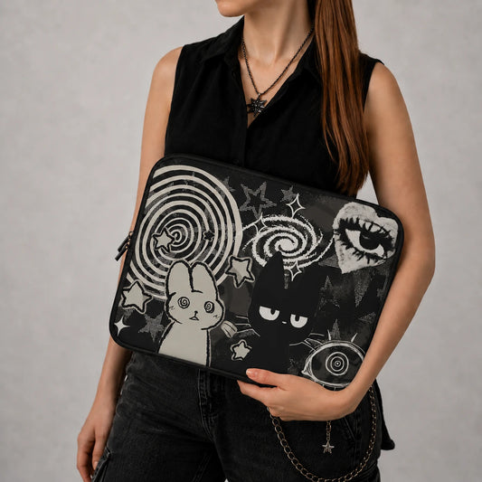 Alternative fashion model holding a gothic laptop sleeve featuring a black cat, hypnotic bunny, celestial spirals, stars and grunge-inspired monochrome artwork.