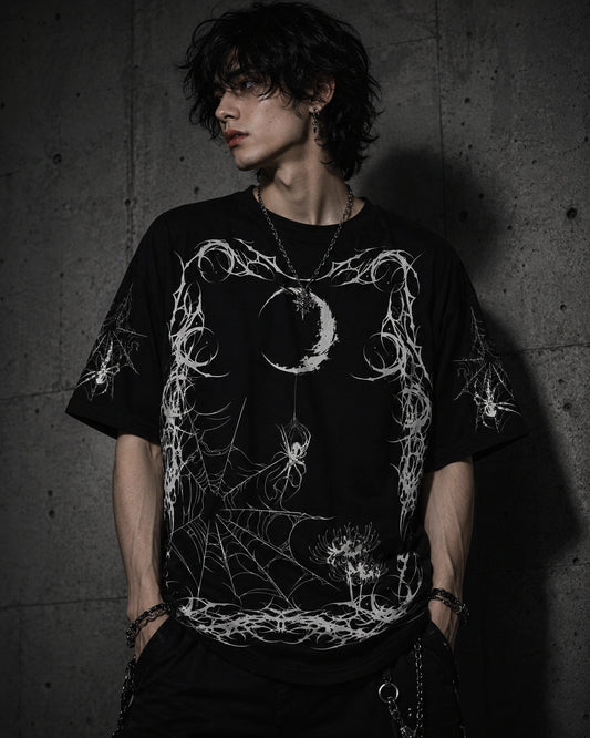 Male model wearing oversized black gothic spider web shirt featuring crescent moon, spider artwork and grunge streetwear style.