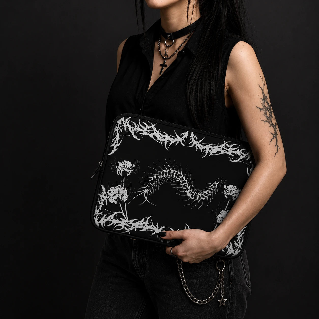Gothic centipede laptop sleeve with alternative black metal inspired frame, spider lily flowers and centipede illustration, held by an alternative goth woman in black clothing.