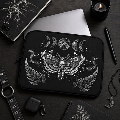Gothic death moth laptop sleeve featuring skull moth artwork, moon phases and centipede illustrations, displayed in a dark alternative workspace with black accessories.