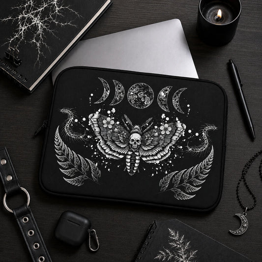 Gothic death moth laptop sleeve featuring skull moth artwork, moon phases and centipede illustrations, displayed in a dark alternative workspace with black accessories.
