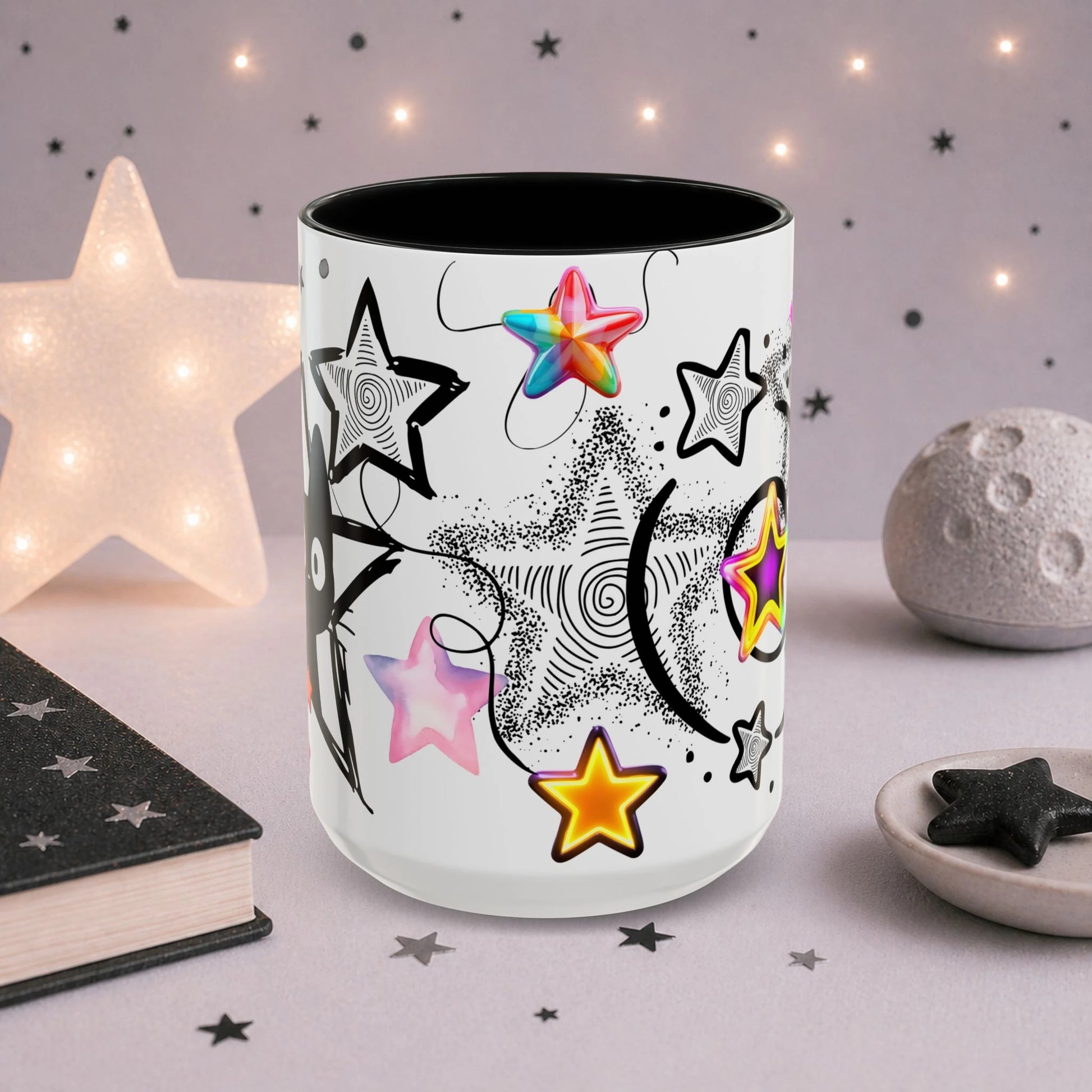 Alternative kawaii cat mug with colorful star illustrations, black and white celestial artwork and pastel goth aesthetic, shown in a soft-lit decorative scene.