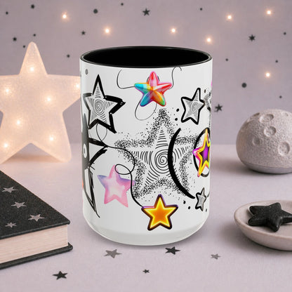 Alternative kawaii cat mug with colorful star illustrations, black and white celestial artwork and pastel goth aesthetic, shown in a soft-lit decorative scene.