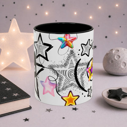 Celestial gothic cat mug featuring colorful holographic stars, black swirl details and dreamy space-inspired artwork, photographed in a cozy aesthetic setting.