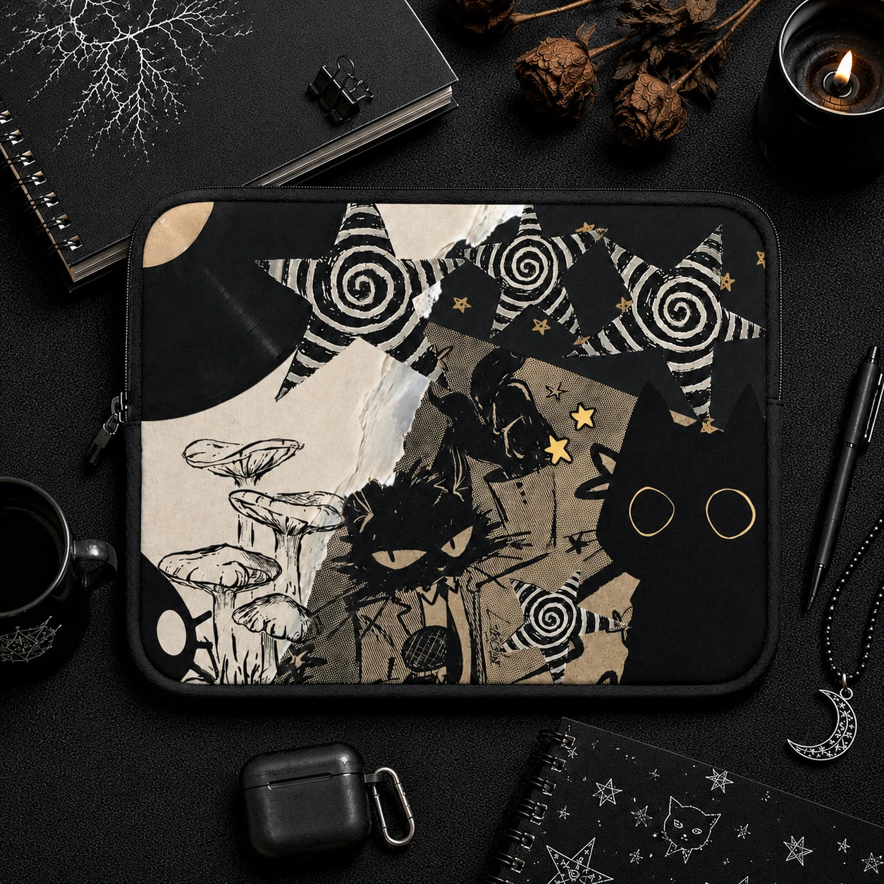 Gothic black cat laptop sleeve with celestial stars, mushrooms and dark collage artwork displayed in a black aesthetic workspace with notebooks, candle and accessories.