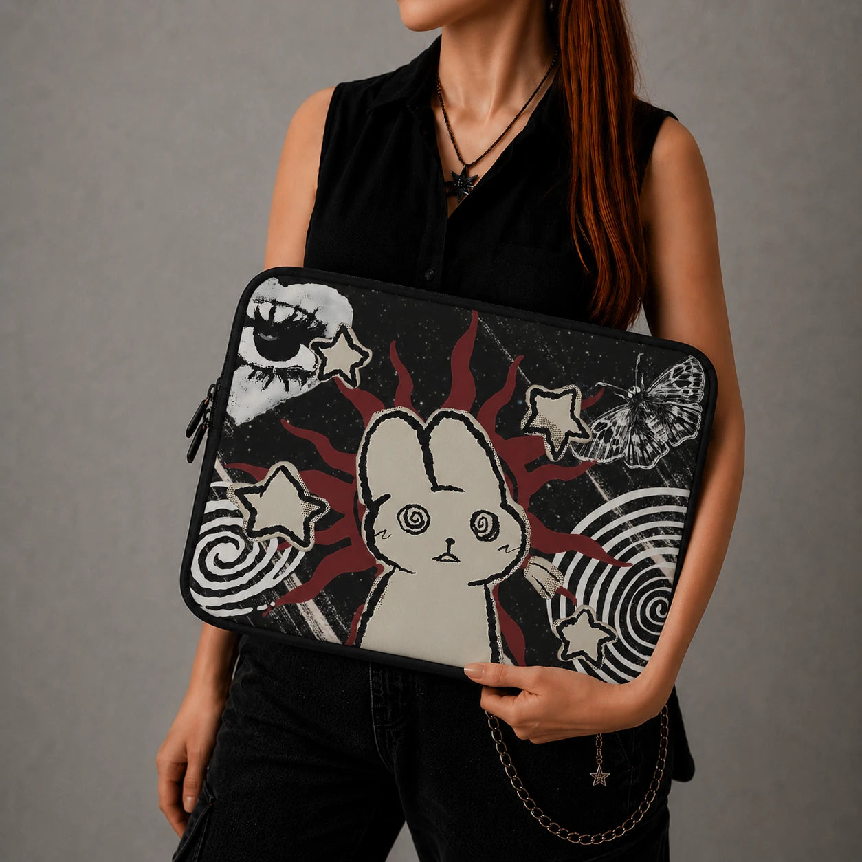 Woman holding a gothic aesthetic laptop sleeve featuring a hypnotic bunny illustration, celestial stars, butterfly artwork and dark alternative design elements.