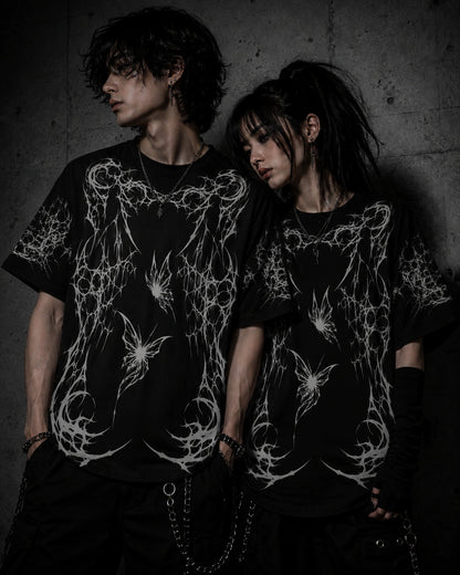 Alternative fashion couple wearing matching oversized gothic butterfly graphic t-shirts in dark streetwear aesthetic.