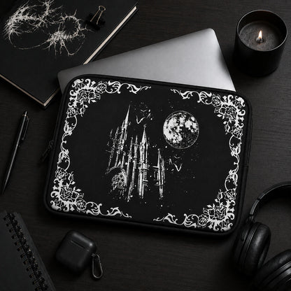 Black gothic laptop sleeve featuring a moonlit castle, bats and floral gothic border, styled in a dark academia workspace with notebook, candle and headphones, ideal for alternative and gothic aesthetics.