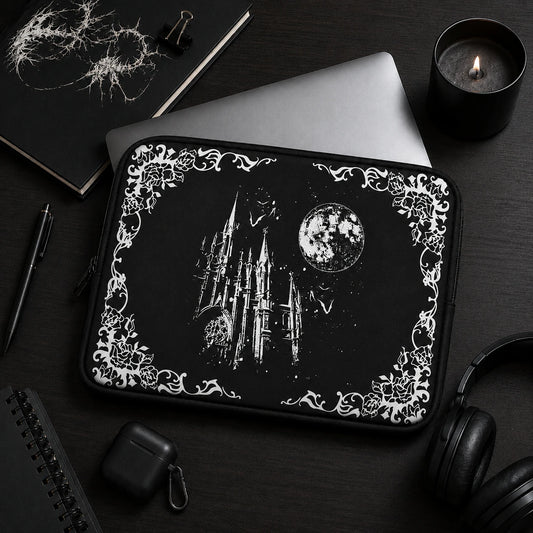 Black gothic laptop sleeve featuring a moonlit castle, bats and floral gothic border, styled in a dark academia workspace with notebook, candle and headphones, ideal for alternative and gothic aesthetics.