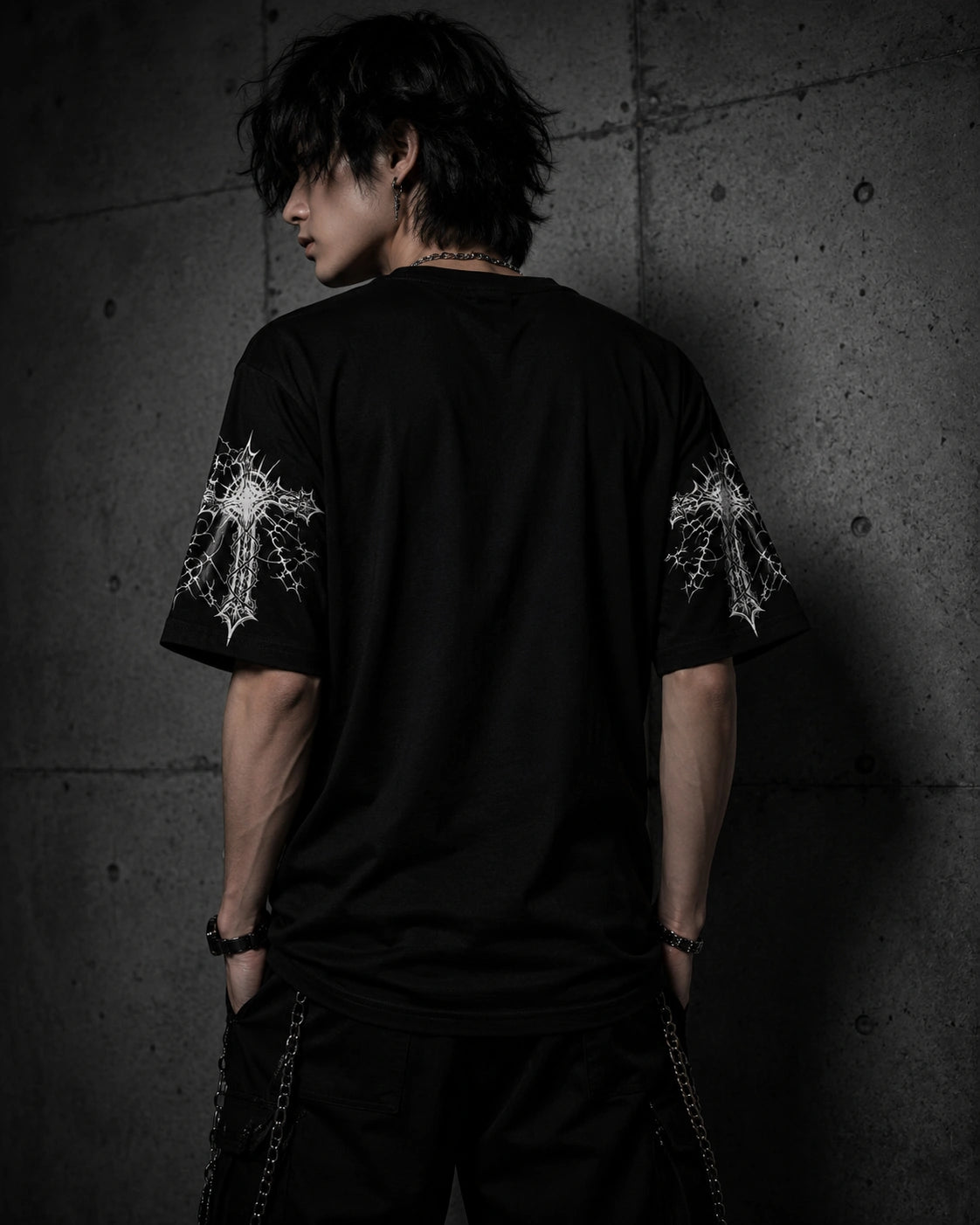 Back view of oversized black gothic t-shirt with white sleeve graphics in dark alternative fashion aesthetic.