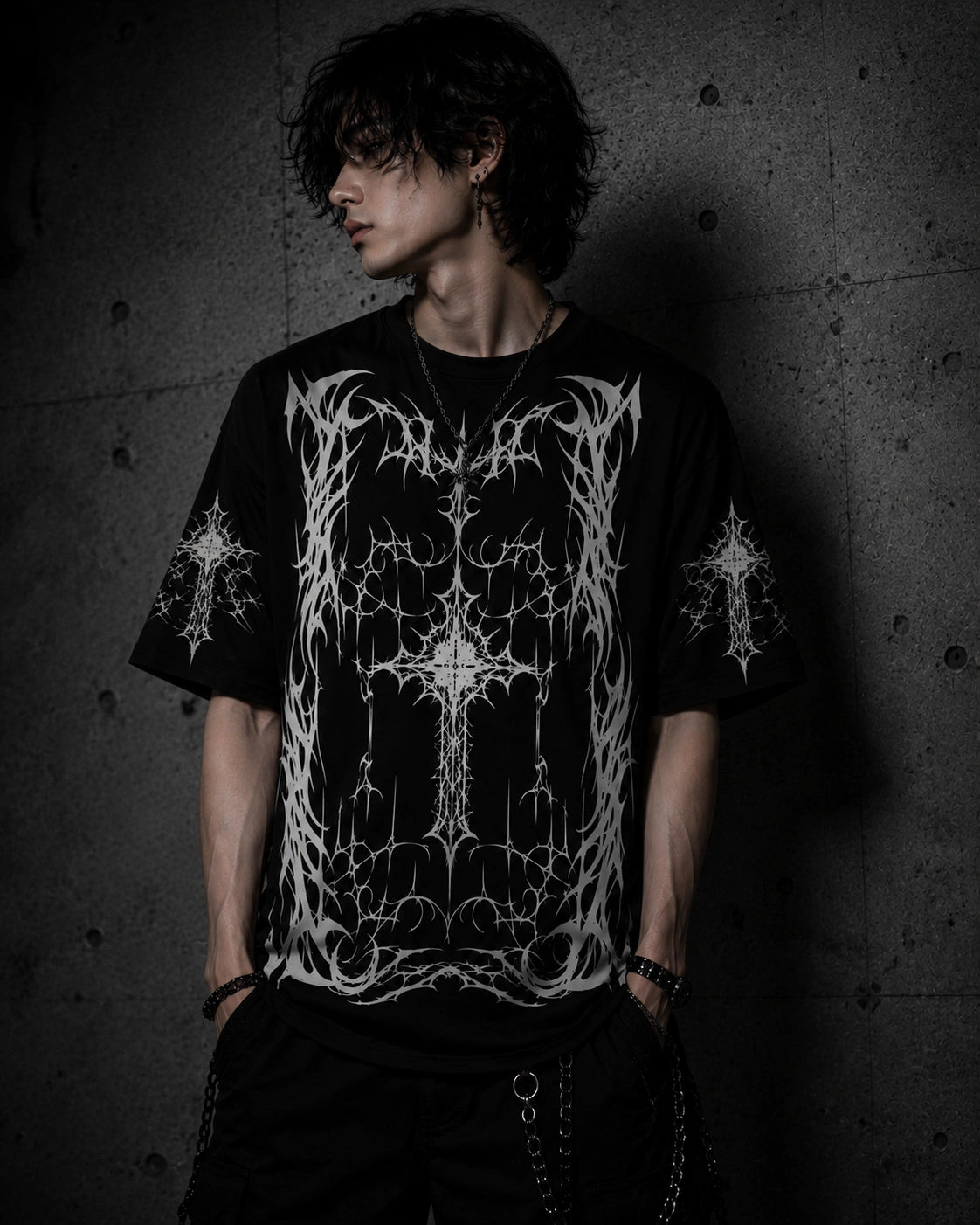 Male model wearing oversized black gothic cross t-shirt featuring detailed white occult-inspired artwork and dark streetwear style.