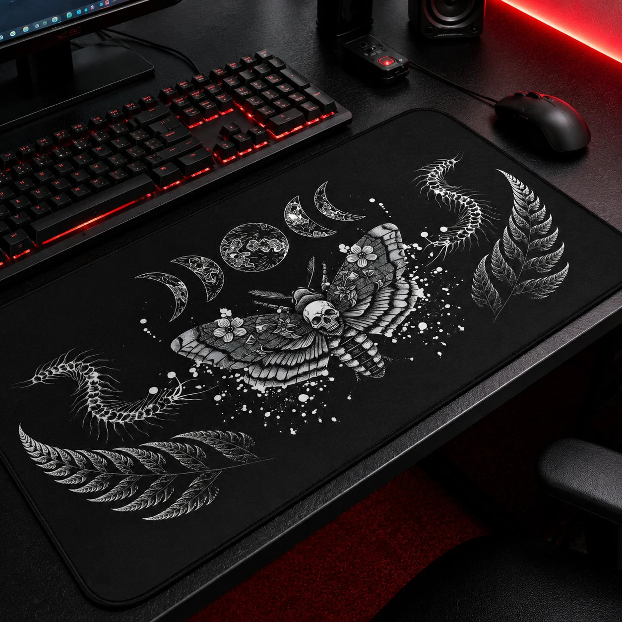 Gothic black gaming mousepad featuring a detailed death's-head moth with skull motif, lunar phases, fern leaves, and centipede illustrations in white ink on a black background. Large extended desk mat for dark academia, gothic, witchcore, and alternative gaming setups with embroidered edges and smooth surface.