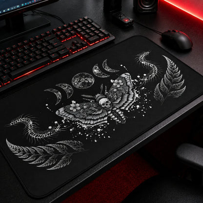 Gothic black gaming mousepad featuring a detailed death's-head moth with skull motif, lunar phases, fern leaves, and centipede illustrations in white ink on a black background. Large extended desk mat for dark academia, gothic, witchcore, and alternative gaming setups with embroidered edges and smooth surface.