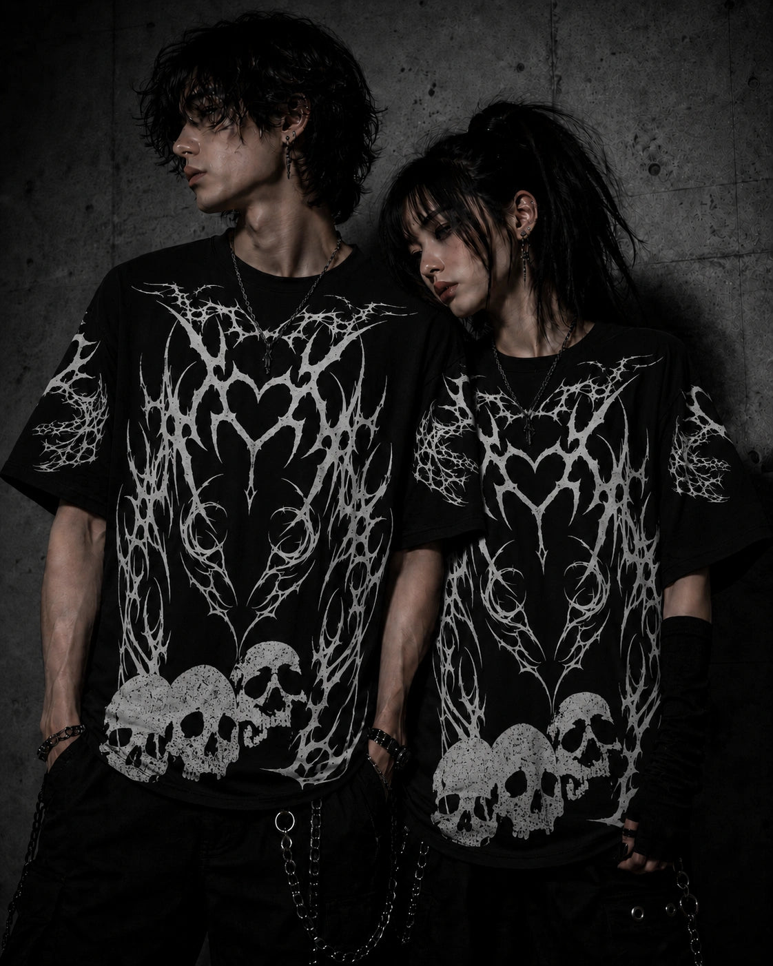 Alternative fashion couple wearing matching oversized gothic skull and tribal heart graphic t-shirts.