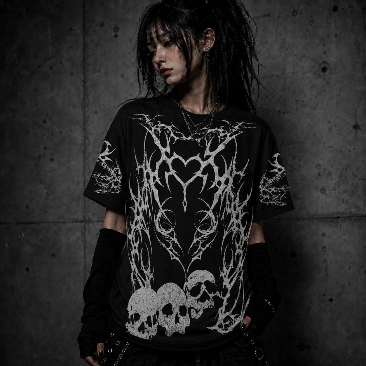 Female model wearing black gothic oversized t-shirt featuring tribal heart artwork and distressed skull graphics.