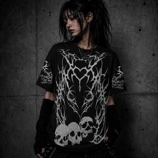 Female model wearing black gothic oversized t-shirt featuring tribal heart artwork and distressed skull graphics.