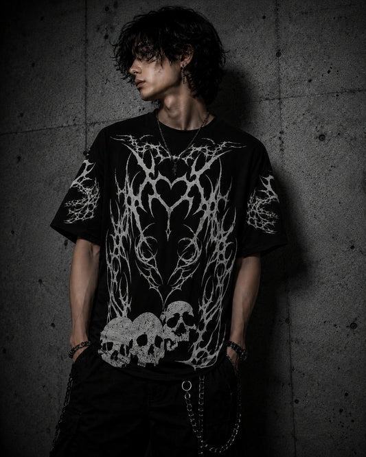 Male model wearing oversized gothic skull shirt with tribal heart design and grunge streetwear aesthetic.