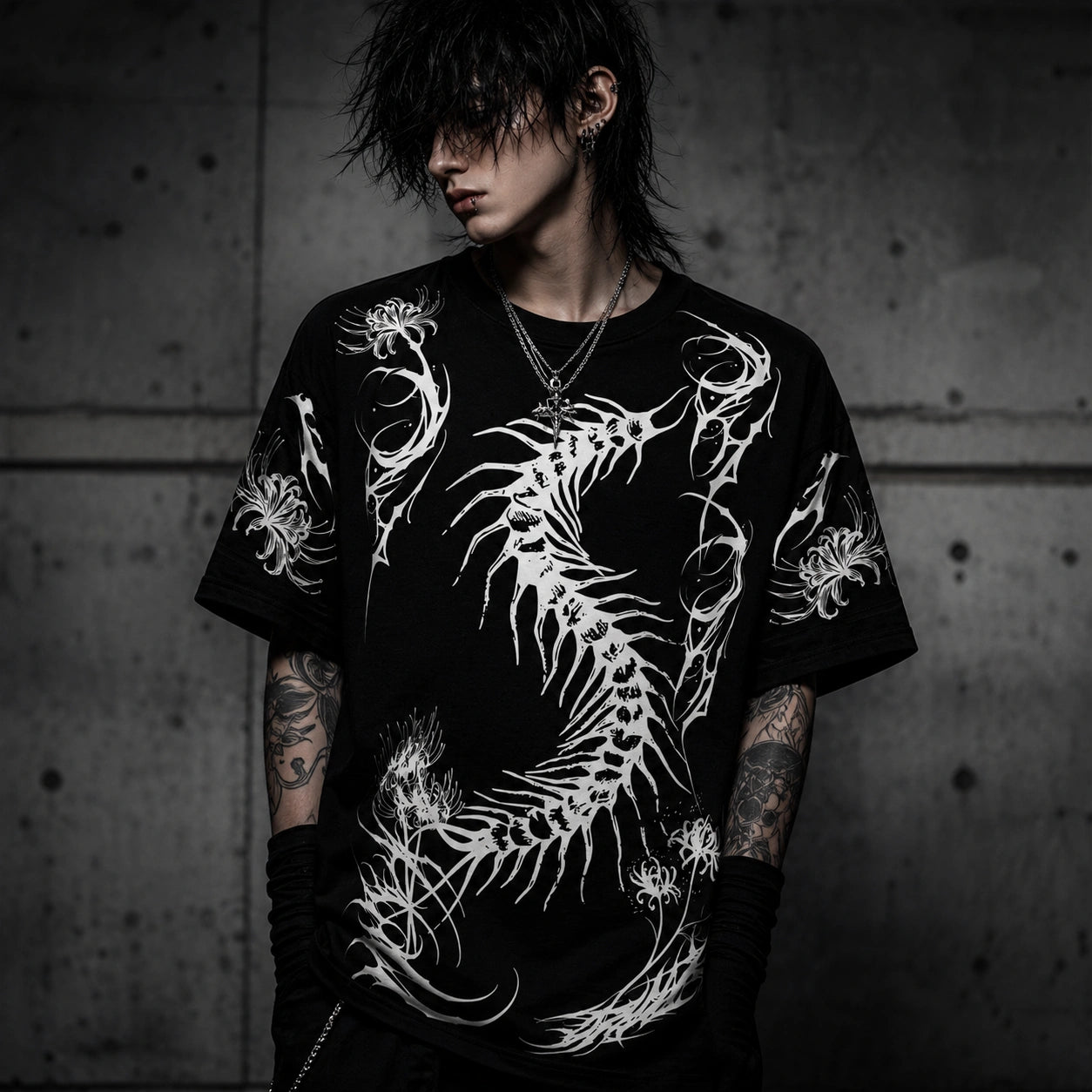 Male model wearing oversized black gothic graphic t-shirt featuring a large white centipede skeleton design in dark streetwear style.