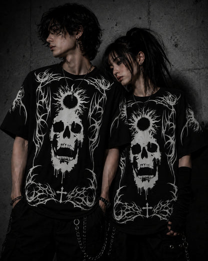 Alternative fashion couple wearing matching oversized black gothic skull graphic t-shirts with white occult-inspired artwork.