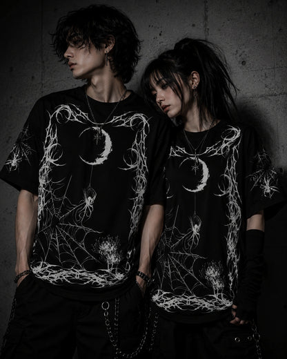 Alternative fashion couple wearing matching oversized gothic spider web graphic t-shirts with moon and spider artwork.