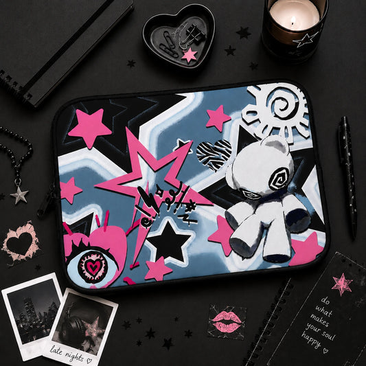 Pastel goth laptop sleeve flat lay surrounded by black aesthetic stationery, candle and alternative decor, featuring pink stars, grunge artwork and cute voodoo doll design.