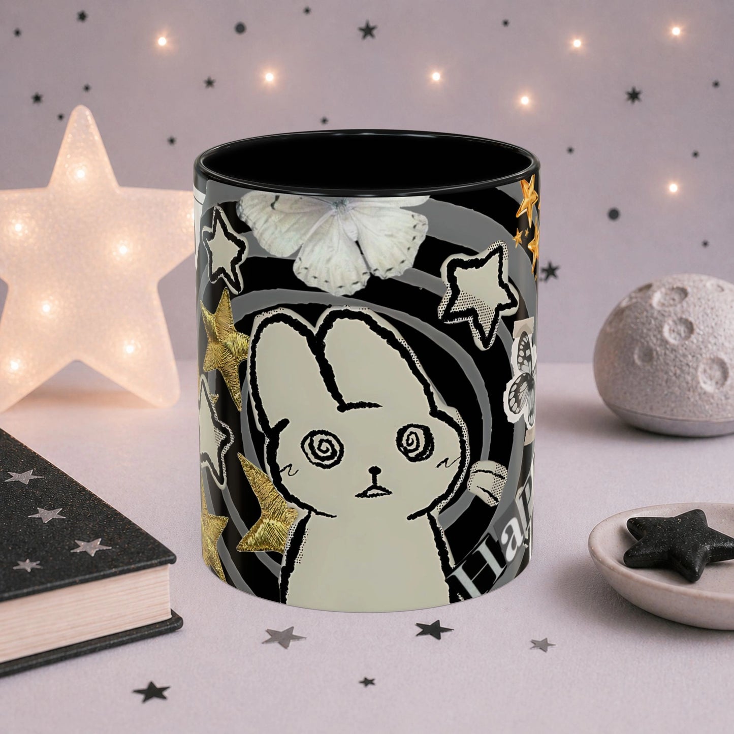Close-up of weirdcore cat mug with spiral eyes, gold stars, butterfly details and black and white collage aesthetic design.