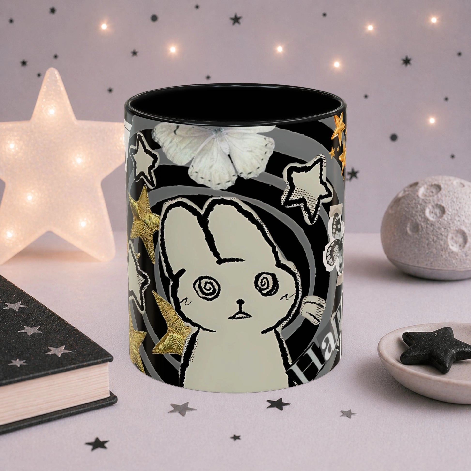 Close-up of weirdcore cat mug with spiral eyes, gold stars, butterfly details and black and white collage aesthetic design.